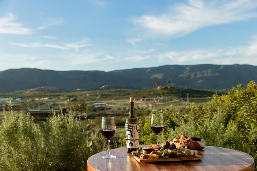 a table with two glasses of wine and a plate of food at Banyan Tree Veya, Valle de Guadalupe in Valle de Guadalupe