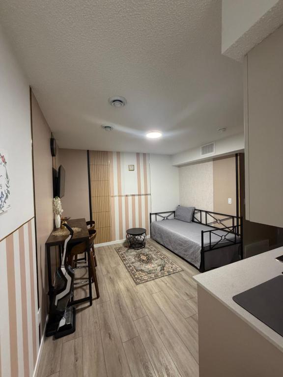 a small room with a bed and a desk and a kitchen at Haverims Cozy and Neat Basement in Edmonton