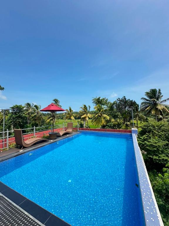 a large blue swimming pool with trees in the background at Feather Villa in Talpe