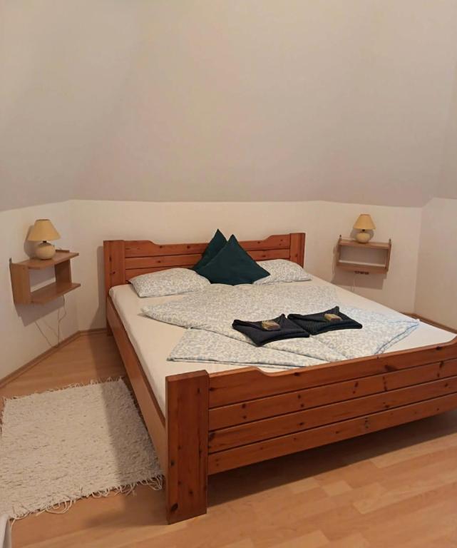 a bedroom with a wooden bed with two towels on it at Elo Apartman in Csokonyavisonta