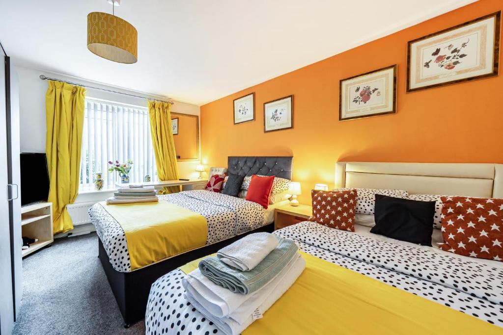 two beds in a room with orange walls at Bright 4 Bedroom Home in Walsall, Free Parking and for EVs in Walsall