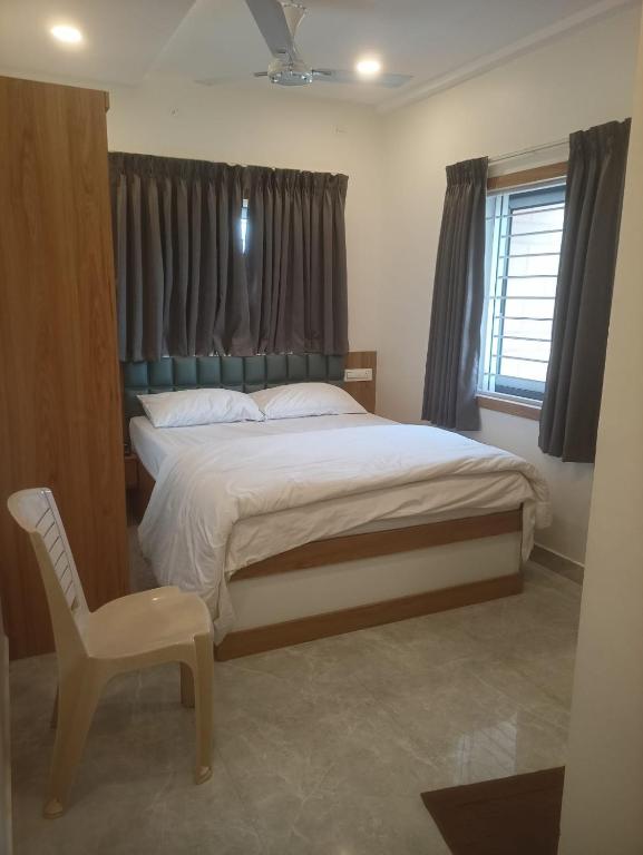 a bedroom with a bed and a chair and a window at The Royal Pavilion Hotel in Kanipakam