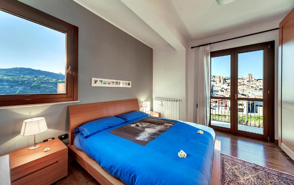 a bedroom with a blue bed and a large window at Suite La perla degli Iblei in Giarratana