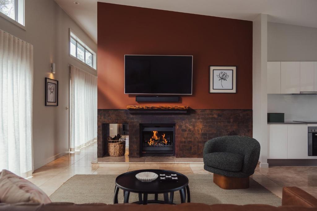 a living room with a fireplace with a tv above it at Clayfields Hunter Valley in Pokolbin