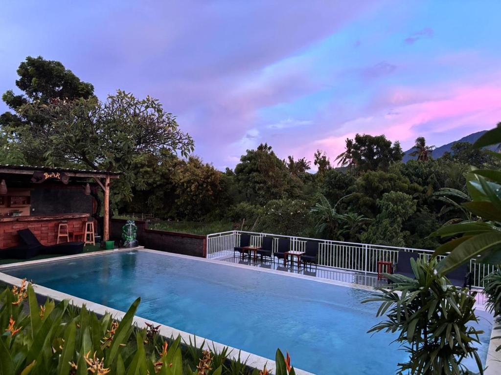 a swimming pool with a sunset in the background at Eco Moringa Garden in Banyuwedang