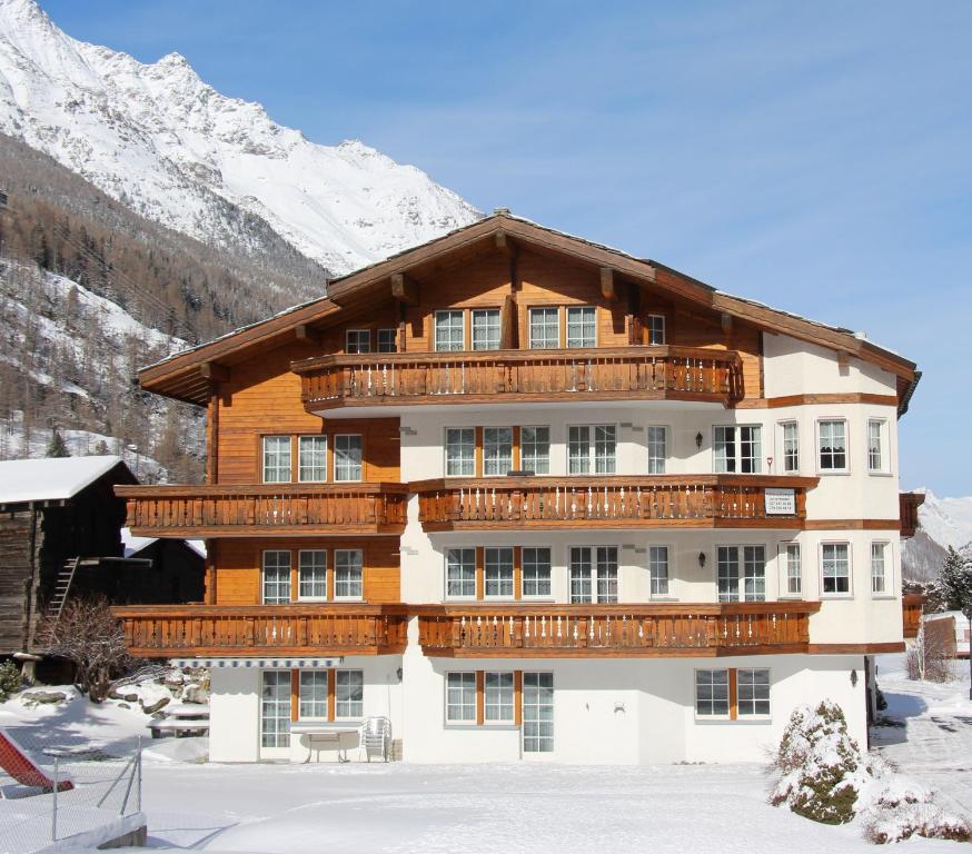 un gran edificio con balcones de madera en la nieve en Apartments Arcadia, en Saas-Grund