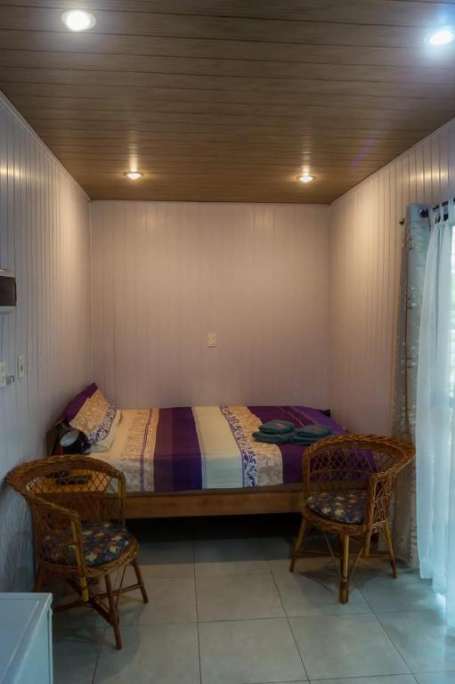 a bedroom with a bed and two chairs at Hotel Restaurant Paraiso TINY in Villarrica
