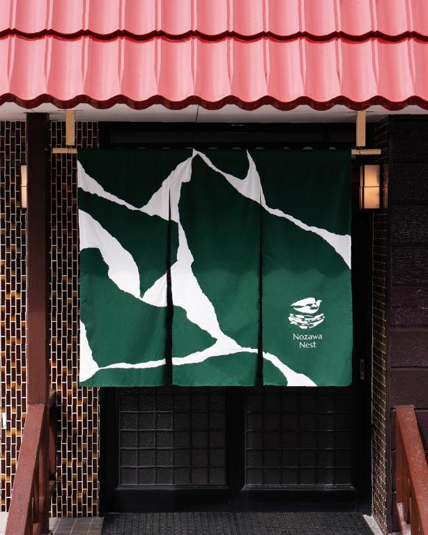 a green and white flag on the front of a building at Nozawa Nest in Nozawa Onsen