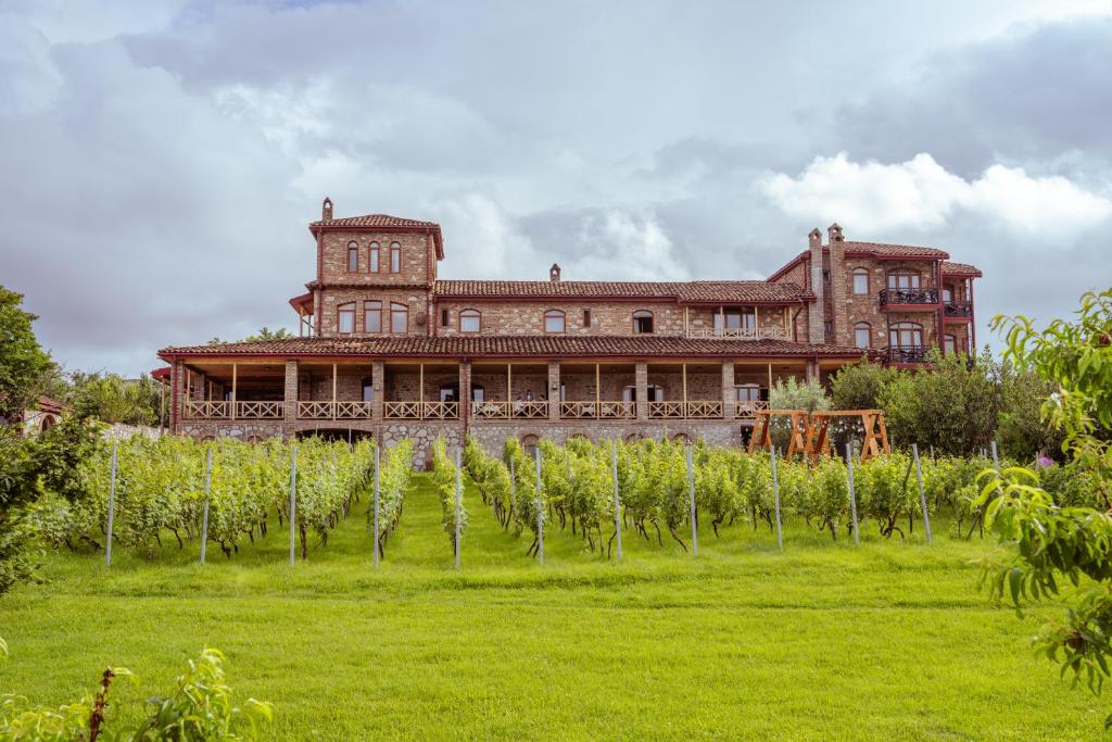 a large brick building with a field of palm trees at Schuchmann Wines Château,Villas & SPA in Telavi