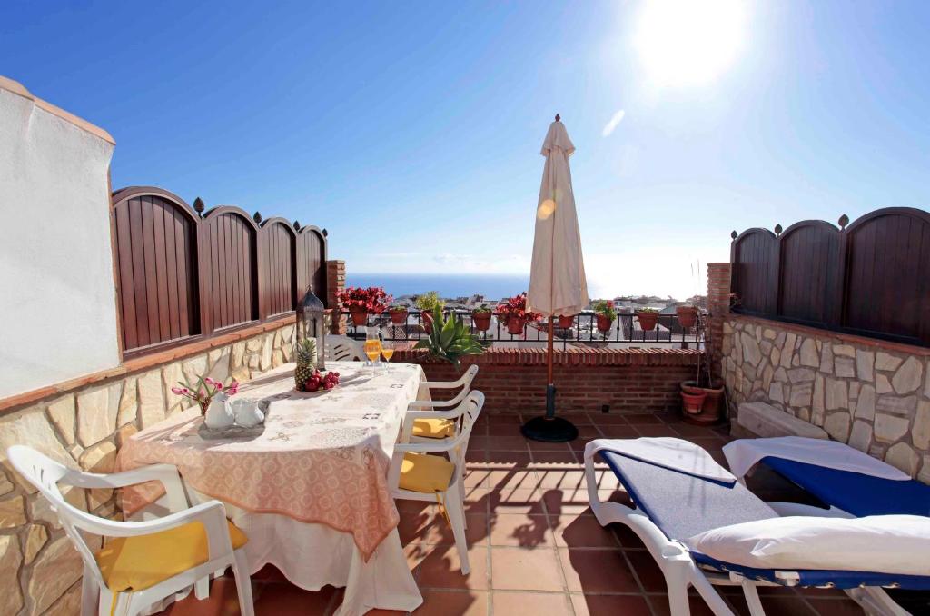 eine Terrasse mit einem Tisch, Stühlen und einem Sonnenschirm in der Unterkunft Hotel Casa Rosa in Benalmádena