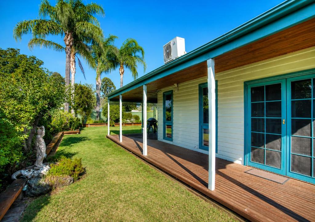 a porch of a house with palm trees at Wandew - Echuca Holiday Homes in Echuca