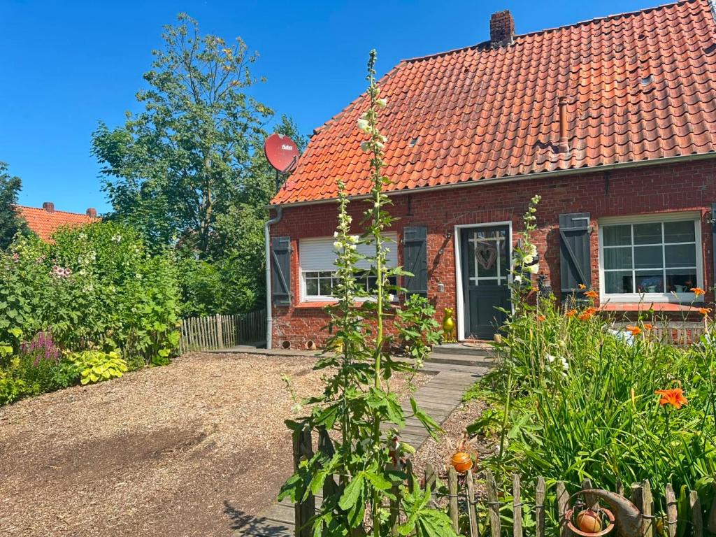 a red brick house with a garden in front of it at Huus an`t Dörpsdiek in Krummhörn