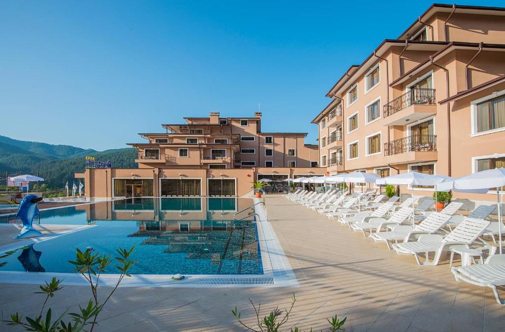 un complejo con una piscina con tumbonas blancas en Park Hotel and SPA Vella Hills, en Velingrad