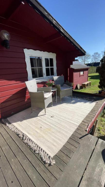 a deck with two chairs and a couch on a house at Solberga red cottage in Solberga