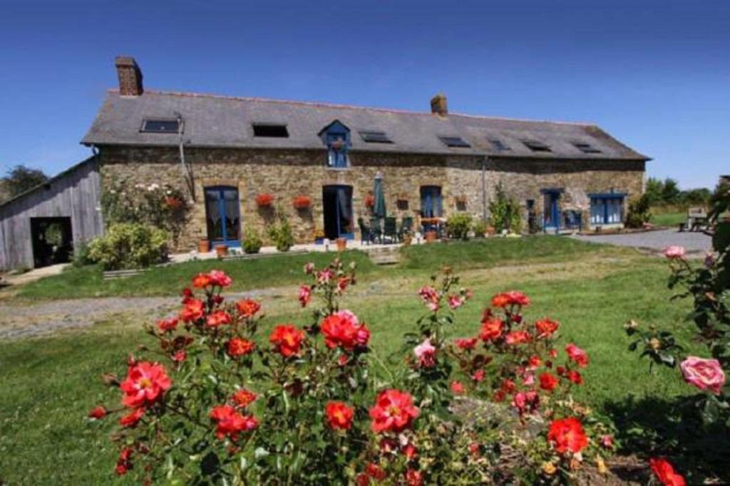 a stone house with red flowers in front of it at Chambre d'Hôte La Boulière in Martigné-Ferchaud