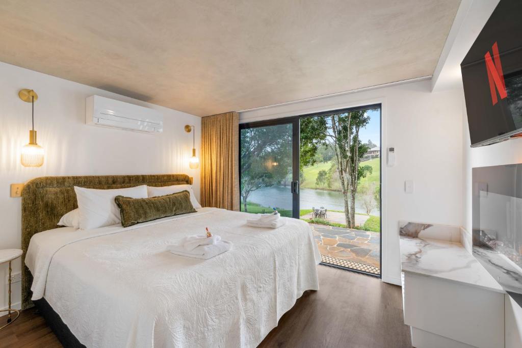 a bedroom with a white bed and a large window at Lakes Edge Retreat in Yungaburra