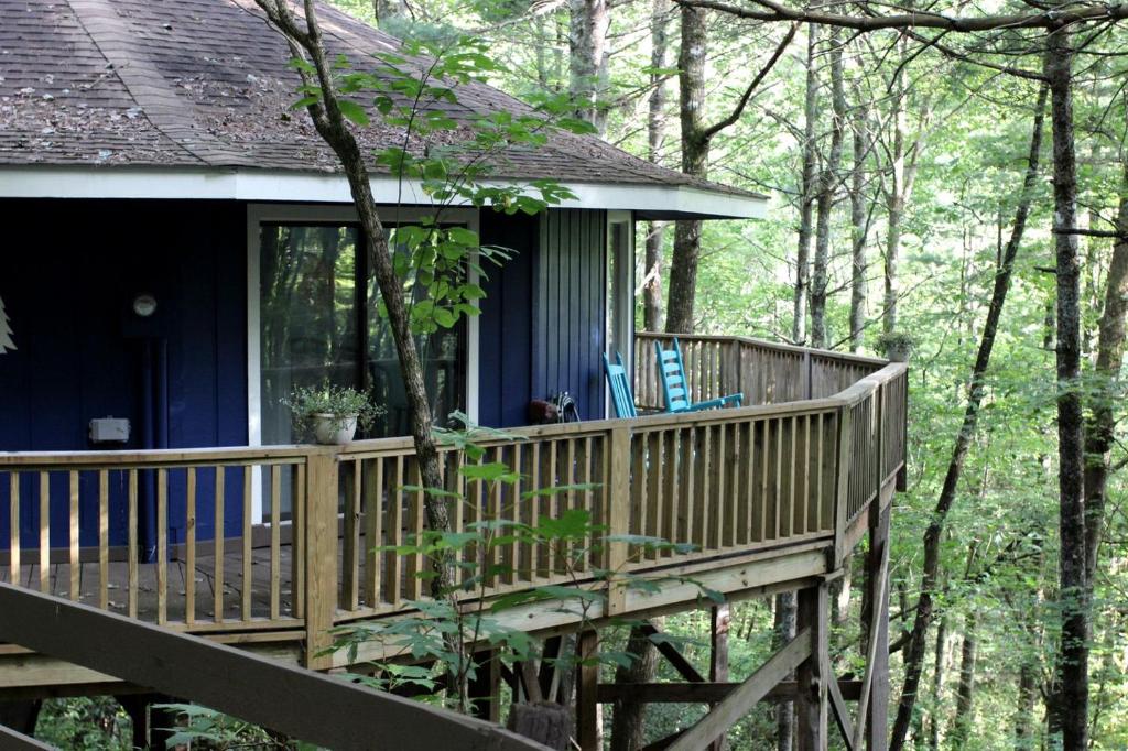 a blue house with a deck in the woods at Rustic Tree Top Cabin in Sky Valley, Georgia in Sky Valley
