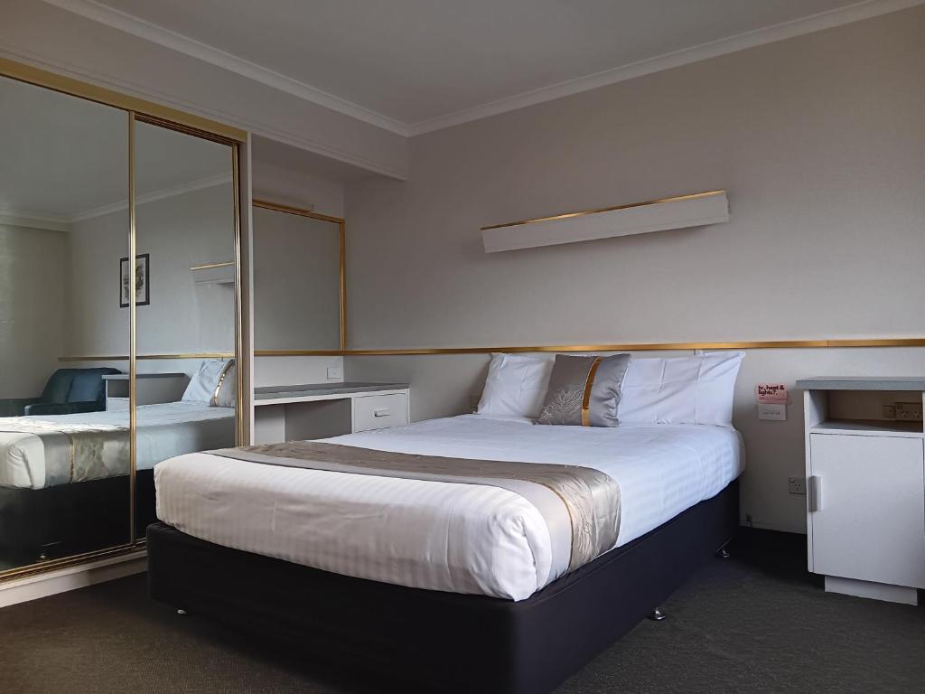 a bedroom with a large bed and a mirror at Parklane Motel in Launceston