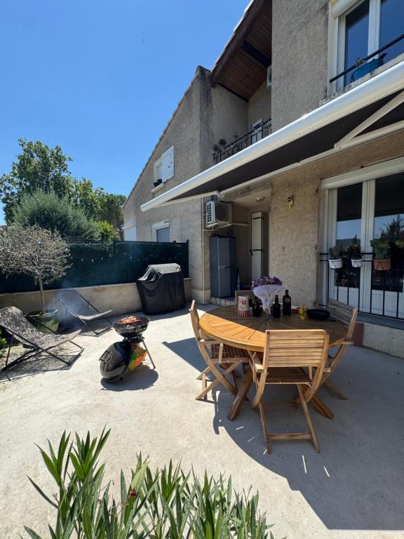 a patio with a wooden table and chairs in front of a house at Au cocon du verdon, T2 in Gréoux-les-Bains
