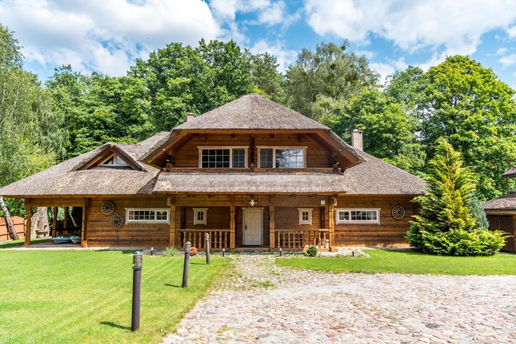 a log home with a thatched roof at Močiutės sodyba in Latežeris