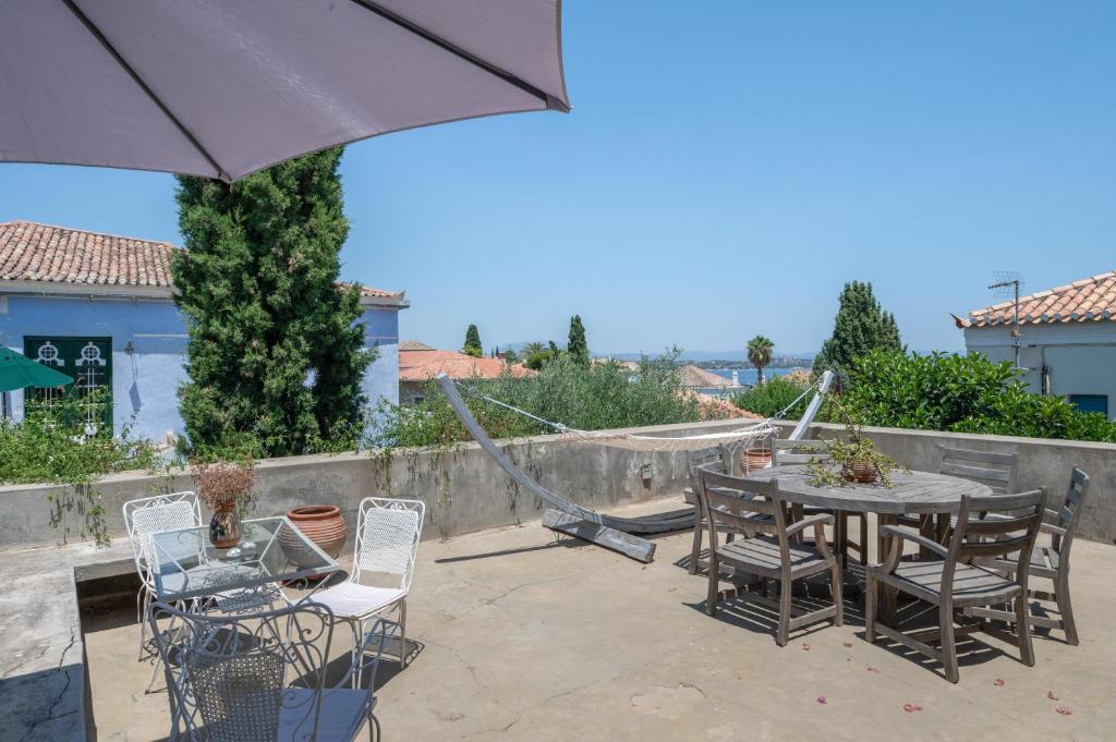 a patio with a table and chairs and an umbrella at Spetses Estia Orloff in Spetses