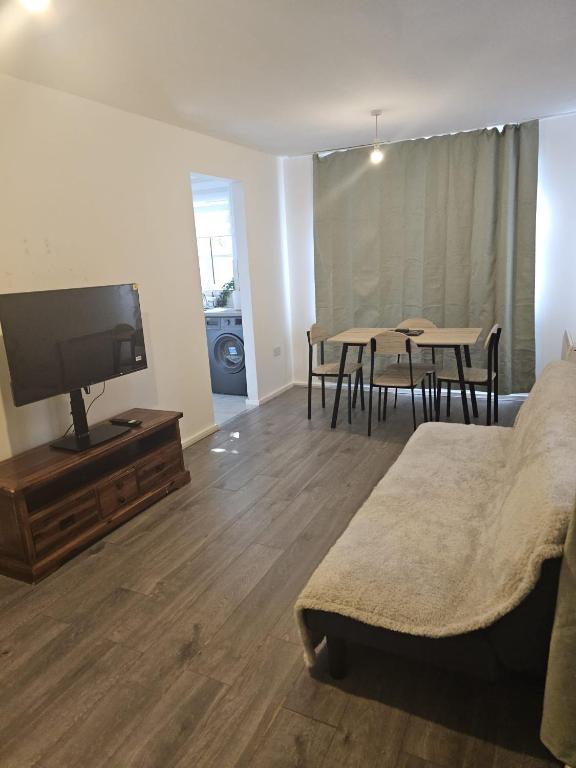 a living room with a bed and a flat screen tv at 2bdr Ground Floor Flat in Edmonton free Parking and WiFi in Ponders End