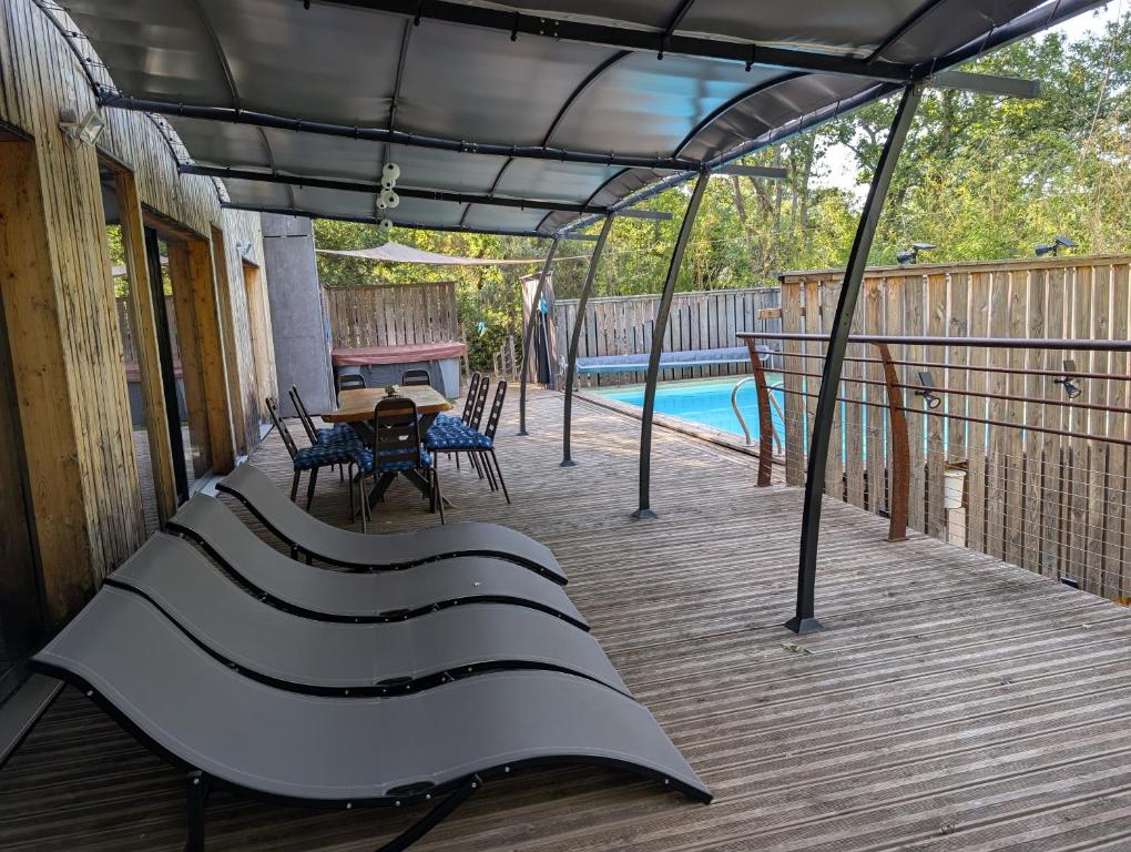 a covered deck with a table and a pool at Villa Mammouth in Saint Alban Auriolles
