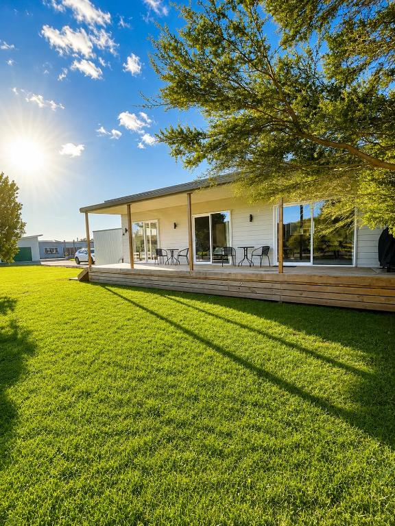 a house with a large yard in front of it at Bach At 45 in Ahipara