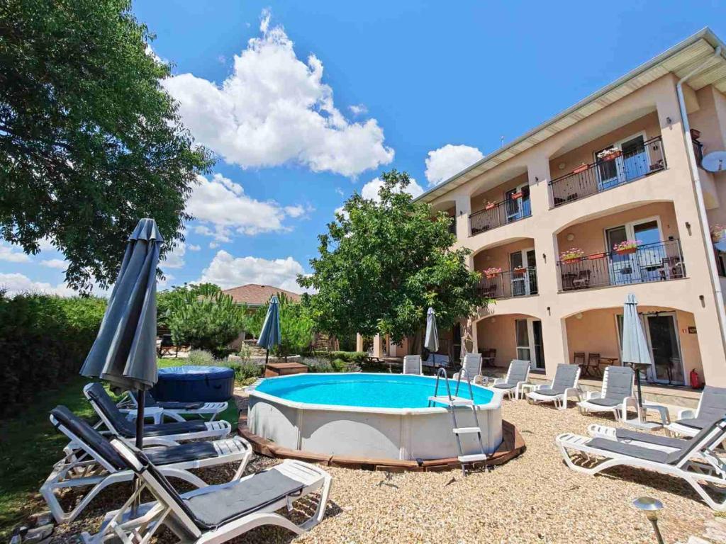 a pool with chairs and umbrellas in front of a building at Къща за гости Крапец in Krapets