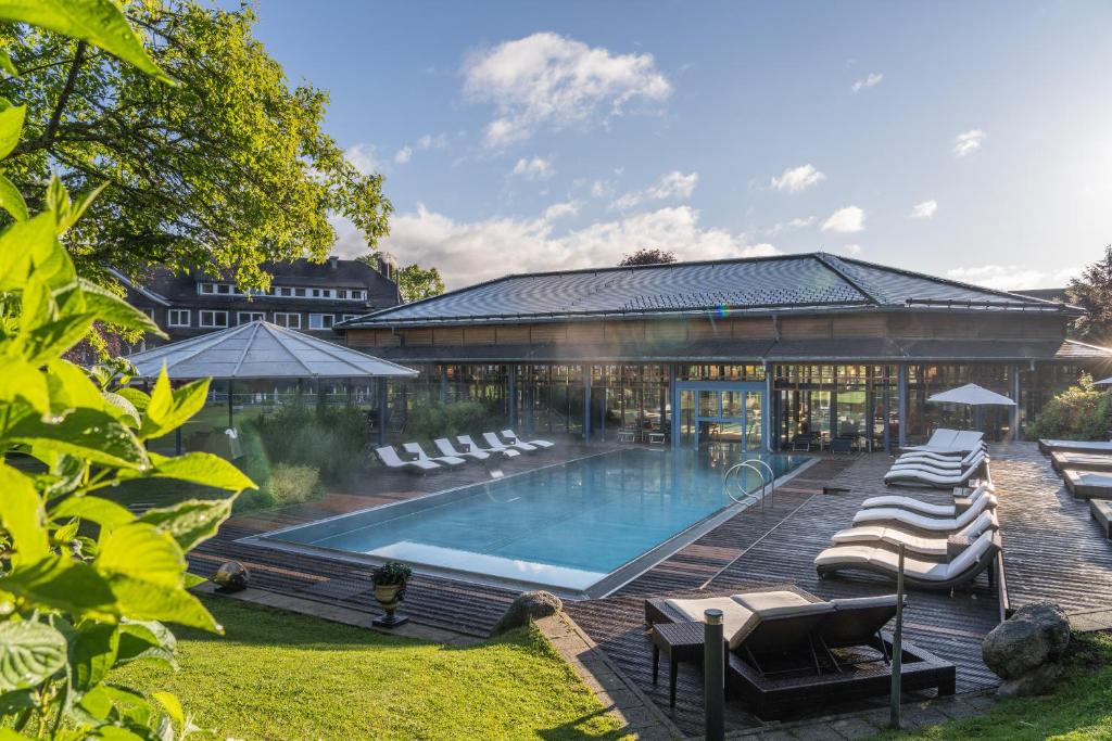 a pool with lounge chairs next to a building at Parkhotel Adler in Hinterzarten