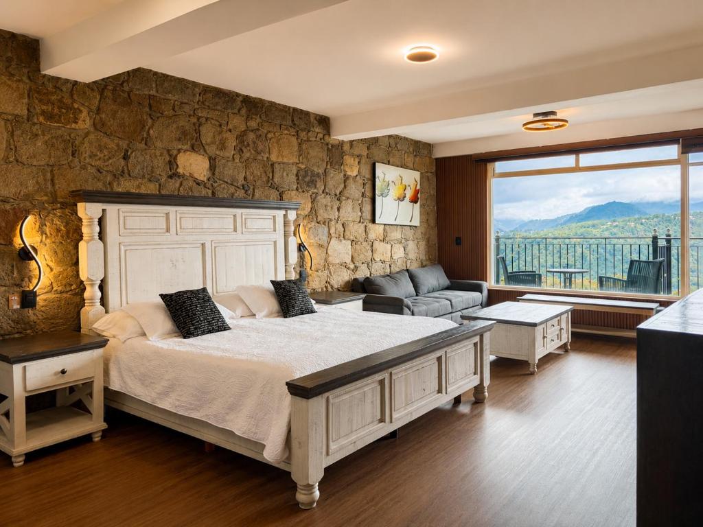 a bedroom with a large bed and a stone wall at Vista Zacatlan Hotel in Zacatlán