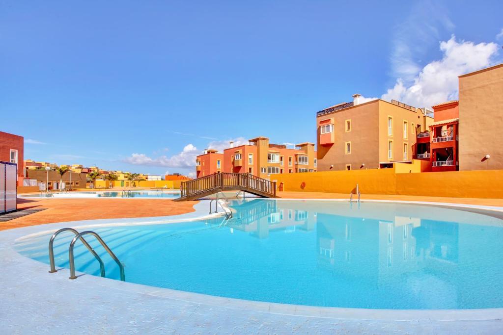 a large swimming pool with buildings in the background at Salitre y lava in Corralejo