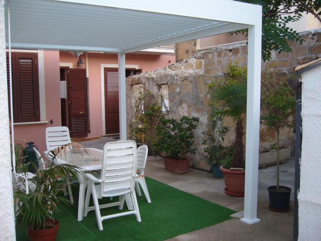 een patio met een tafel en stoelen en een muur bij Casa indipendente con ampia veranda in Portopalo