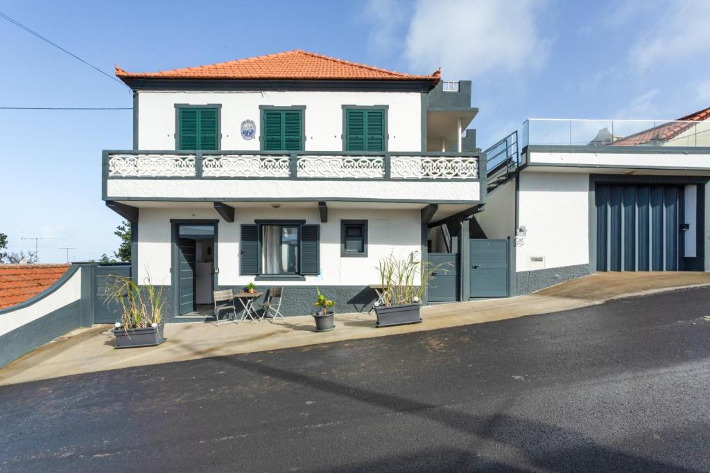 a white house with a balcony on a street at Casa Pereira in Ponta do Pargo