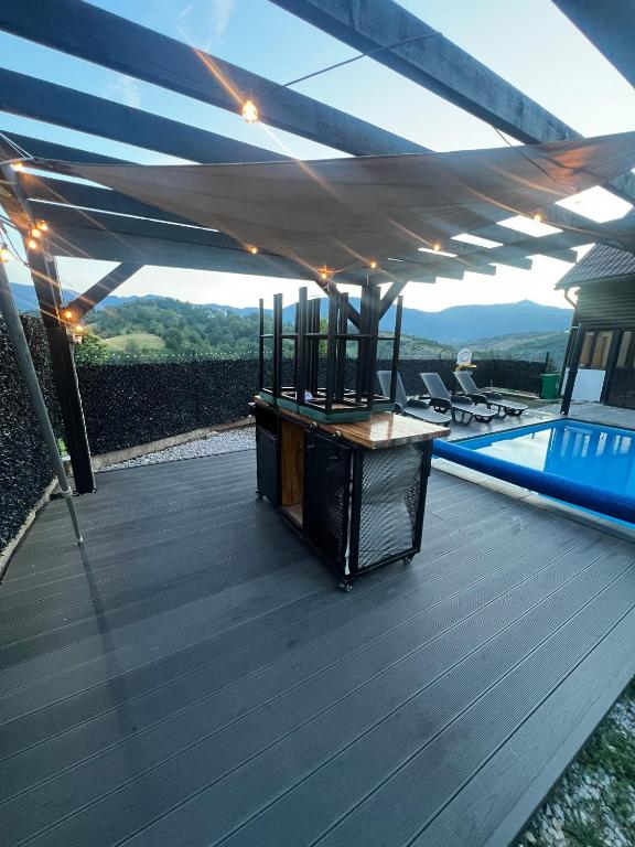 a wooden deck with awning over a swimming pool at The Alpine Poolhouse in Trnovo