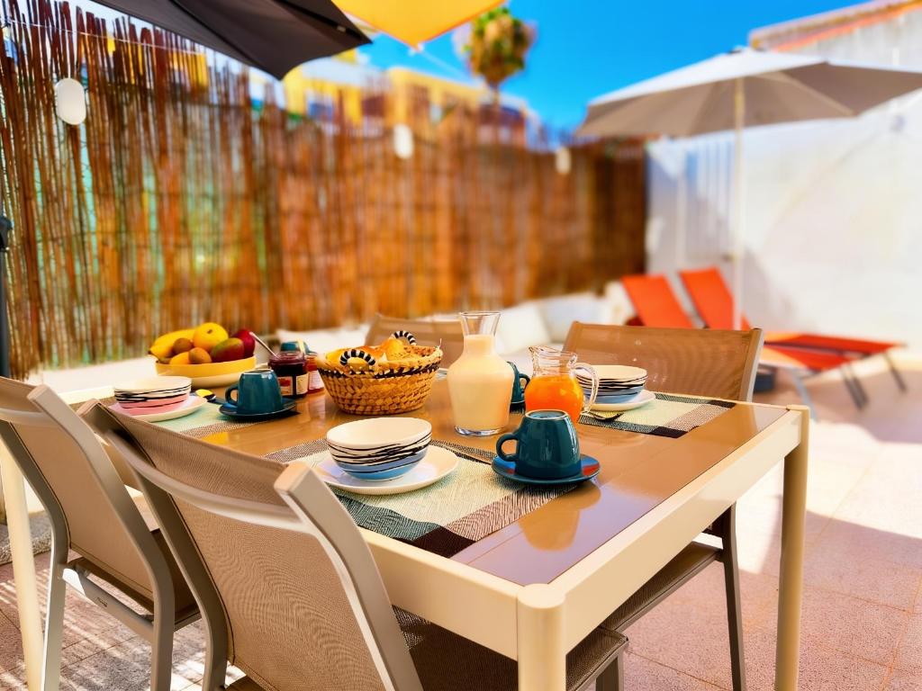 a table with a bowl of fruit and a glass of milk at Central Olhão Home - Private Spacious Sunlit Patio in Olhão