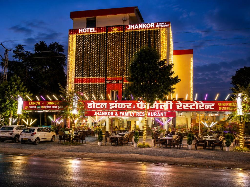 a hotel is lit up at night with tables and chairs at Jhankor Hotel in Sīkar