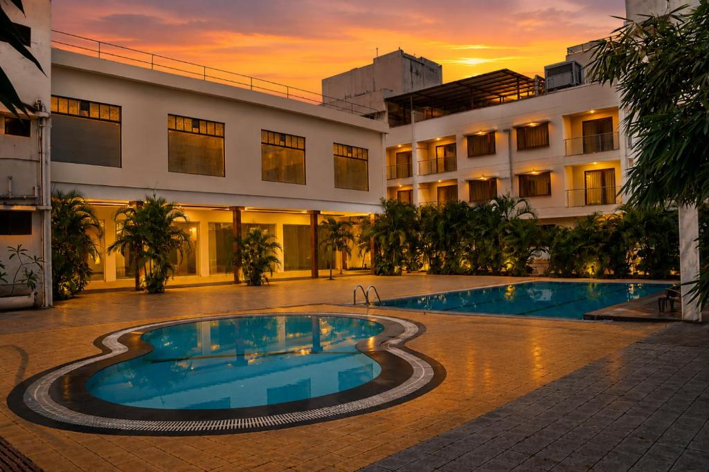 a hotel with a swimming pool in front of a building at Pushpak Resort in Shirdi