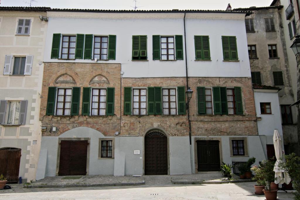 an old white building with green shuttered windows at Residenza Basiglio in Ceva