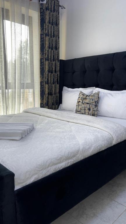 a large bed with a black headboard in a bedroom at Authentic Galore in Ongata Rongai 