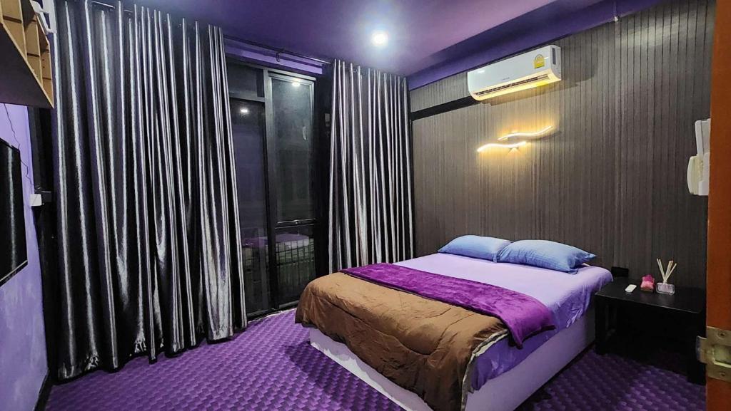 ein lila Schlafzimmer mit einem Bett und einem Fenster in der Unterkunft Ber Ben House in Bang Su