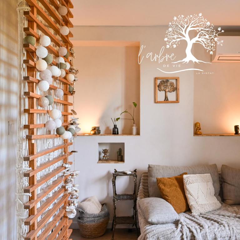 a living room with a couch and a wall with a tree sign at Mon petit cocon au bord de l'eau in La Ciotat