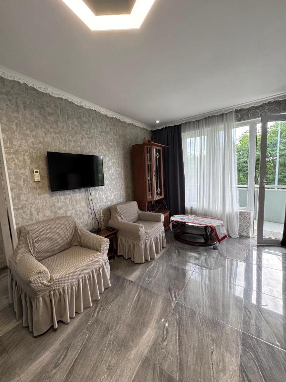 a living room with two chairs and a flat screen tv at მყუდრო აპარტამენტი ანაკლიაში, Cozy Apartment in Anaklia in Zugdidi
