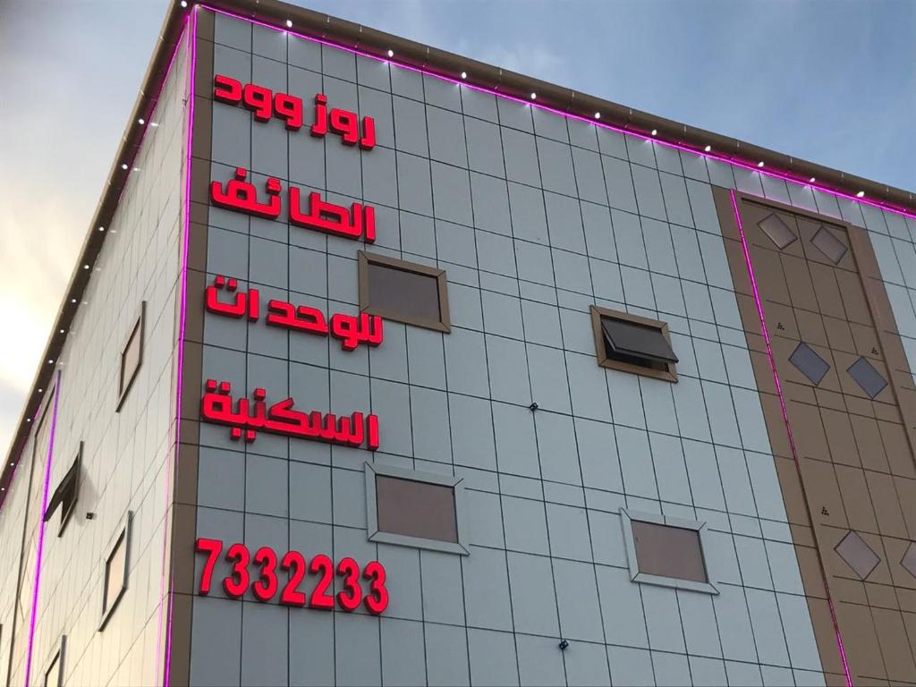 a building with red signs on the side of it at Rose Wood in Taif