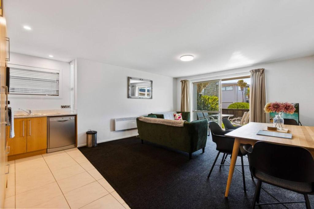 a living room with a couch and a table at Resort-Style 2BR Alpine Apt | Pool, Spa & Garage in Wanaka