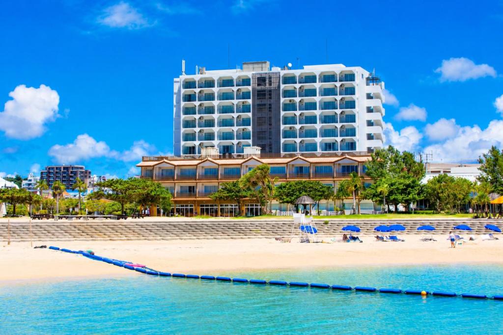 a hotel on a beach with chairs and umbrellas at Condominium Hotel Monpa in Chatan