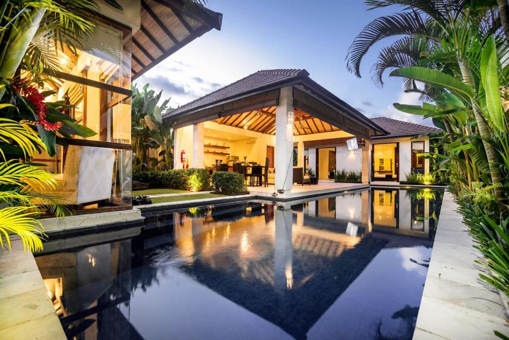 a swimming pool in front of a house at Arama Riverside in Legian