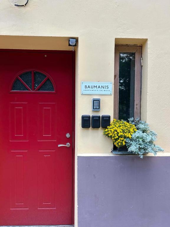 a red door and a sign on the side of a building at Baumanis klasika in Valmiera