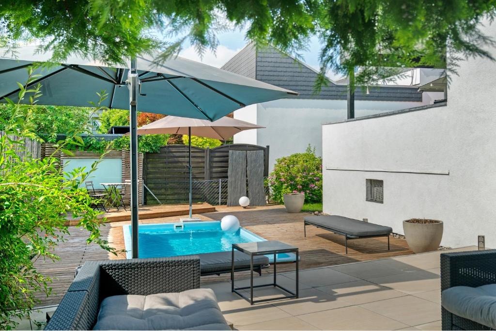 a patio with a swimming pool and an umbrella at Modern House, Pool, Garden in Burgdorf