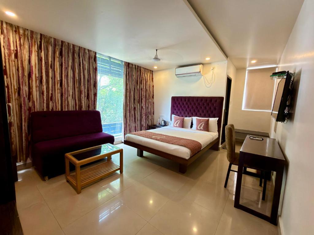 a bedroom with a bed and a couch and a chair at Astra Hotels and Suites HSR Sector 1 in Bangalore